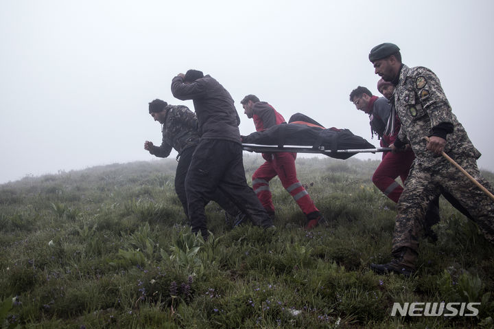 [바르자간=AP/뉴시스] 20일(현지시각) 이란 북서부 바르자간에서 에브라힘 라이시 대통령 일행이 탑승한 헬기가 추락한 가운데 구조대원들이 시신을 옮기고 있다. 2024.05.21.