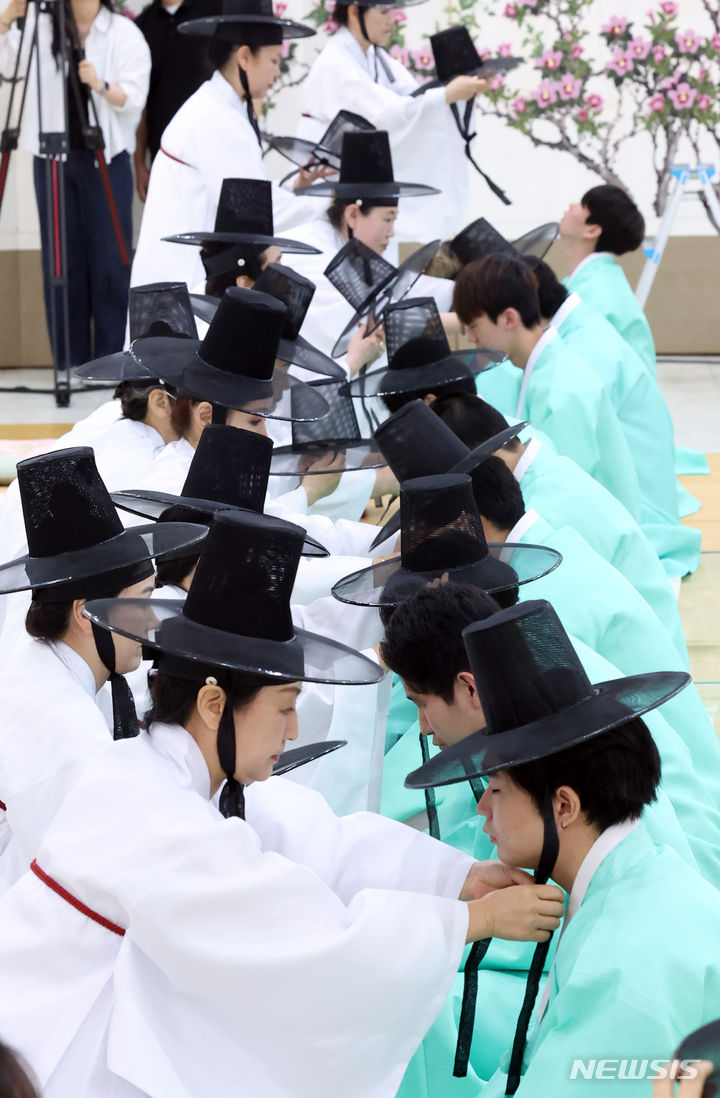 [부산=뉴시스] 하경민 기자 = 제52회 성년의 날인 20일 오후 부산 사상구 부산시여성문화회관 대강당에서 열린 '전통 성년례'에 참가한 남성 성년자들이 갓을 쓰는 의식인 관례에 임하고 있다. 2024.05.20. yulnetphoto@newsis.com
