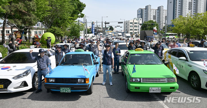 [광주=뉴시스] 박기웅 기자 = 제44주년 5·18민중항쟁 민주기사의 날 기념식이 열린 20일 오후 광주 북구 옛 무등경기장 앞에서 택시기사들이 구호를 외치고 있다. 이들은 44년 전 5·18민주화운동 당시 전남도청 앞 금남로를 가득 메우고 광주시민들의 저항을 촉발한 차량 행렬 시위를 재현했다. 2024.05.20. pboxer@newsis.com