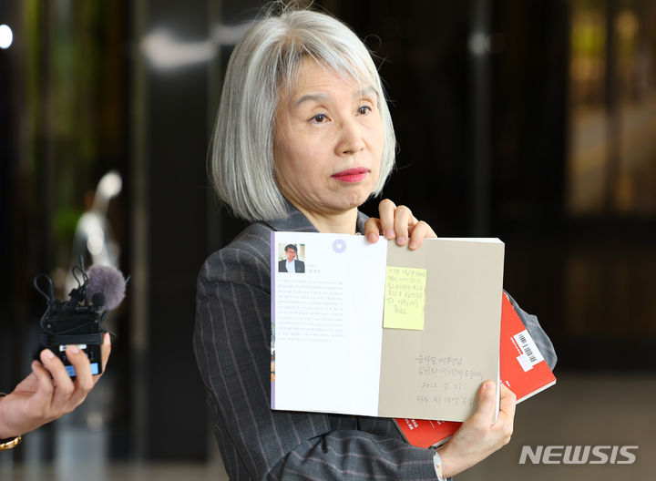 [서울=뉴시스] 황준선 기자 = 권성희 변호사가 21일 오후 서울 서초구 서울중앙지방검찰청에서 열린 참고인 조사에 출석하며 지난 2022년 윤석열 대통령 부부가 살던 서울 서초구 아파트 분리수거장에서 김건희 여사가 선물 받은 것으로 추정되는 최재형 목사의 저서 등을 들어보이고 있다. 2024.05.21. hwang@newsis.com