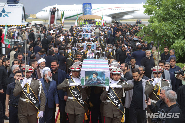 [타브리즈=AP/뉴시스] 이란 대통령실이 공개한 사진에 이란 혁명수비대(IRGC) 대원들이 21일(현지시각) 이란 동아제르바이잔주 타브리즈에서 에브라힘 라이시 대통령의 사진으로 덮인 관을 옮기고 있다. 이란 정부는 이날 오전부터 라이시 대통령 등 지난 19일 헬기 사고로 숨진 희생자들에 대한 장례 일정에 들어가 타브리즈 광장에서의 운구 행렬을 시작으로 23일까지 주요 도시 사원에서 장례식을 거행한다. 2024.05.22.