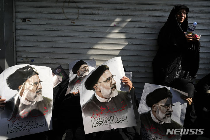 [테헤란=AP/뉴시스] 22일(현지시각) 이란 수도 테헤란에서 고 에브라힘 라이시 대통령과 헬기 추락 사고 희생자들의 장례식이 열려 추모객들이 라이시 대통령의 사진을 들고 있다. 이날 수만 인파가 테헤란을 통과하는 운구행렬을 따른 것으로 알려졌다. 2024.05.22.