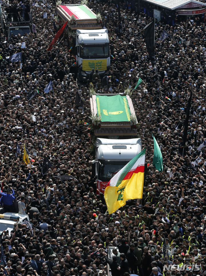 [테헤란=AP/뉴시스] 22일(현지시각) 이란 수도 테헤란에서 열린 고 에브라힘 라이시 대통령과 헬기 추락 사고 희생자들의 장례식에서 시민들이 운구 차량을 따라가고 있다. 2024.05.23.