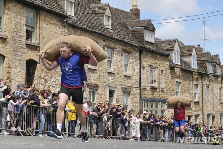 [테트베리=AP/뉴시스] 27일(현지시각) 영국 글로스터셔주 테트베리에서 연례 '울색 레이스'(Woolsack Race)가 열려 참가자들이 울색(양털 포대)을 짊어지고 언덕을 오르고 있다. 1972년 시작된 이 대회는 코로나19로 중단됐다가 재개됐다. 성인 남자는 27㎏, 여자는 16㎏의 포대를 메고 약 256m 코스의 언덕을 달리며 어린이 부문도 있다. 2024.05.28.