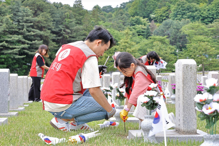 샤롯데 봉사단이 묘비 옆에 태극기를 꽂고 있다.(사진 제공=롯데건설) *재판매 및 DB 금지