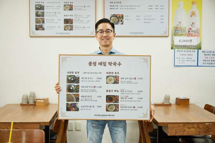 한 외식업주가 바뀐 메뉴판을 들고 포즈를 취하고 있다.(사진=우아한형제들 제공) *재판매 및 DB 금지