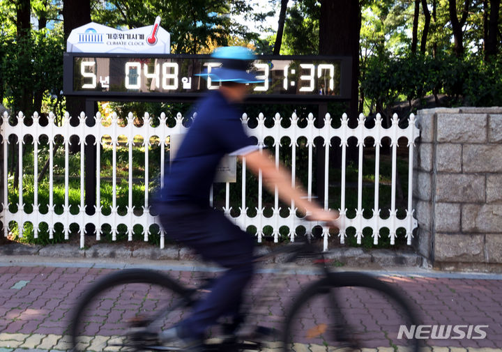 [서울=뉴시스] 조성봉 기자= 세계 환경의 날을 하루 앞둔 4일 오후 서울 여의도 국회 인근에 있는 기후위기시계 앞을 한 시민이 자전거를 타고 지나가고 있다. 2024.06.04. suncho21@newsis.com