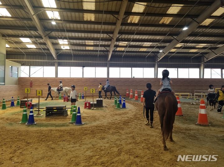 [세종=뉴시스] 김동현 기자 = 안성팜랜드 내에 위치한 실내체험승마장에서 아이들이 승마 체험을 하고 있는 모습.2024.06.06