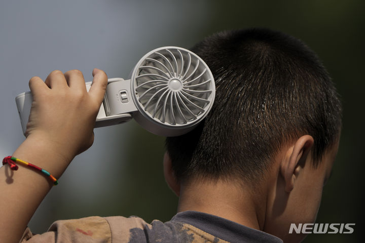 [베이징=AP/뉴시스] 더운 날씨를 보인 10일 중국 베이징 외곽 퉁저우의 한 공원에서 어린이가 선풍기로 더위를 식히고 있다. 2024.06.17.