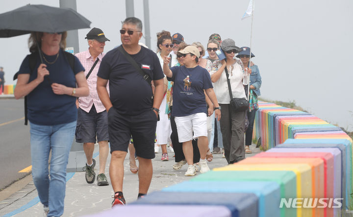 [제주=뉴시스] 우장호 기자 = 제주 해안가를 중심으로 짙은 안개가 드리워진 12일 오전 제주시 무지개해안도로를 찾은 외국인 관광객들이 산책로를 걸어가고 있다. 2024.06.12. woo1223@newsis.com