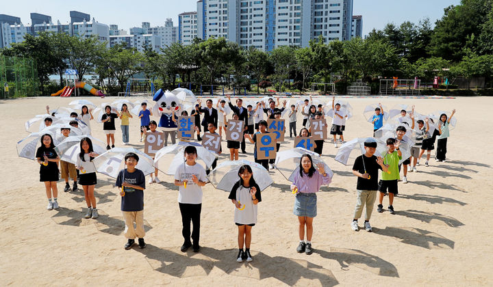 광주 서구 상무초등학교 학생들이 12일 광주신세계에서 폐현수막으로 제작해 배포한 안전우산을 들고 환경보호 퍼포먼스를 하고 있다. (사진=광주신세계 제공) photo@newsis.com *재판매 및 DB 금지