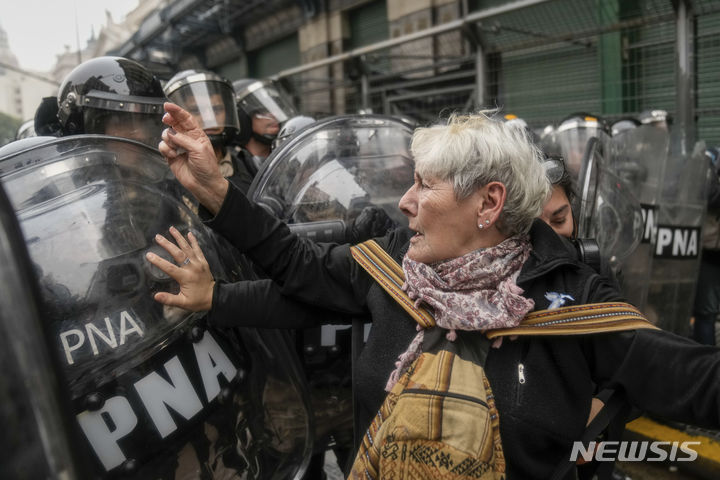 [부에노스아이레스=AP/뉴시스] 12일(현지시각) 아르헨티나 부에노스아이레스 의회에서 국회의원들이 하비에르 마일리 대통령의 개혁안을 논의하는 동안 국회 밖에서 시위 중인 한 여성이 경찰과 충돌하고 있다. 2024.06.13.