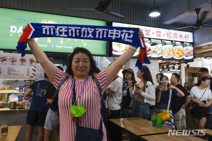 [싱가포르=AP/뉴시스] 14일(현지시각) 싱가포르 축구 국가대표팀의 골키퍼 하산 서니의 아내 아이다 라힘이 운영하는 음식점에 중국인들이 줄 선 가운데 한 축구팬이 기념 촬영을 하고 있다. 중국인들이 '2026 북중미 월드컵' 아시아 지역 예선에서 싱가포르 골키퍼 서니가 태국을 상대로 선방을 펼쳐 그 덕에 중국이 3차 예선에 올라가게 됐다며 그의 음식점에 몰려들어 돈쭐을 내주는 것으로 알려졌다. 2024.06.14.