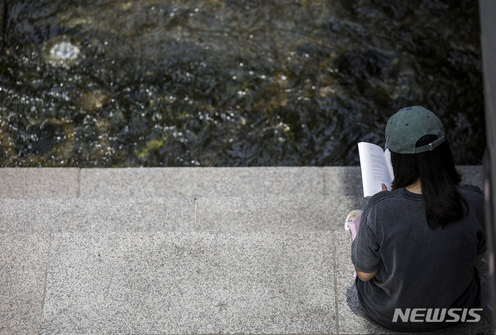 [서울=뉴시스] 정병혁 기자 = 낮 최고기온이 35도로 더운 날씨를 보인 지난 14일 서울 중구 청계천을 찾은 시민이 그늘에서 책을 읽고 있다. 2024.06.14. jhope@newsis.com