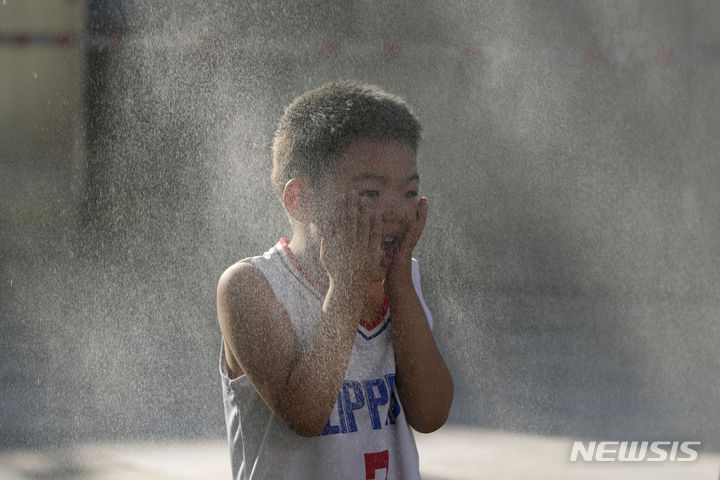 [베이징=AP/뉴시스] 더운 날씨를 보인 15일 중국 베이징에서 한 어린이가 쿨링포그를 맞으며 더위를 식히고 있다. 2024.06.17.