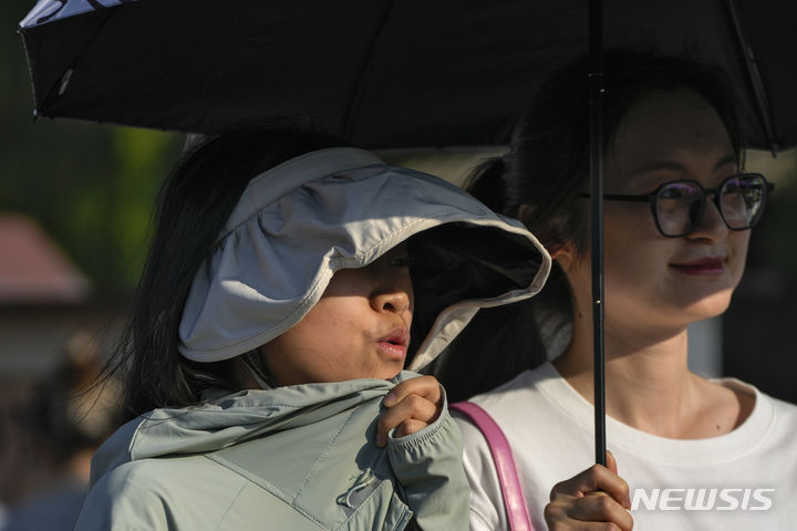 [베이징=AP/뉴시스] 더운 날씨를 보인 16일 중국 베이징에서 한 여성이 자외선 차단용 모자를 쓴 채 이동하고 있다. 2024.06.17.