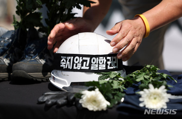 [서울=뉴시스] 김명년 기자 = 지난해 6월 오전 서울 중구 시청 앞에서 열린 '산재 사망 책임 회피 규탄! 서울시·공사의 사과, 재발 방지 촉구!' 기자회견에서 서울교통공사노동조합 조합원이 지난 9일 연신내역 전기실에서 작업 도중 감전사고로 사망한 노동자의 유품에 '죽지 않고 일 할 권리'라는 문구가 적힌 머리띠를 씌우고 있다. 2024.06.17. kmn@newsis.com **기사 내용과 직접 관련 없습니다**