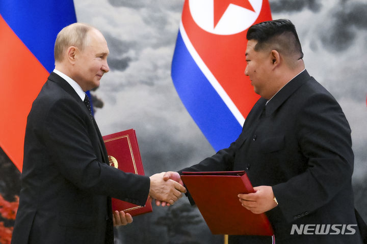 [평양=AP/뉴시스] 블라디미르 푸틴(왼쪽) 러시아 대통령과 김정은 북한 국무위원장이 19일 북한 평양 금수산 영빈관에서 '포괄적 전략 동반자 협정'을 체결한 후 협정서를 들고 악수하고 있다. 2024.06.20.