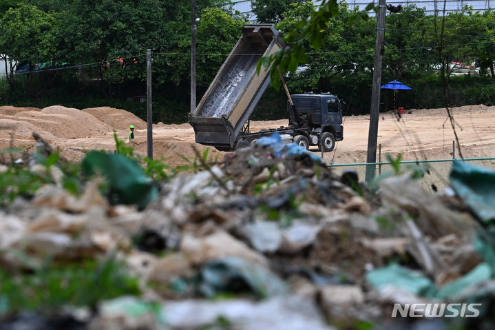 [광주=뉴시스] 이영주 기자 = 광주 서구 풍암동 중앙공원 제1지구 공사현장 주변 야산에서 30여년 전 매립된 쓰레기들이 지난달 배수로 공사 도중 무더기로 발견됐다. 발견된 6000여t 쓰레기는 시공사에서 처리할 방침이나 공사 과정에서 추가로 나오는 쓰레기 처리 여부 등은 협의를 거쳐야 한다. 쓰레기 매립장 주변 공사현장에서 덤프트럭이 흙을 쏟아내고 있다. 2024.06.20.leeyj2578@newsis.com