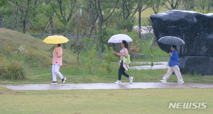 [전주=뉴시스] 김얼 기자 = 선선한 여름 비가 내리는 22일 전북 전주시 전주세병공원에서 시민들이 우산으로 비를 피하며 길을 지나고 있다. 2024.06.22. pmkeul@newsis.com