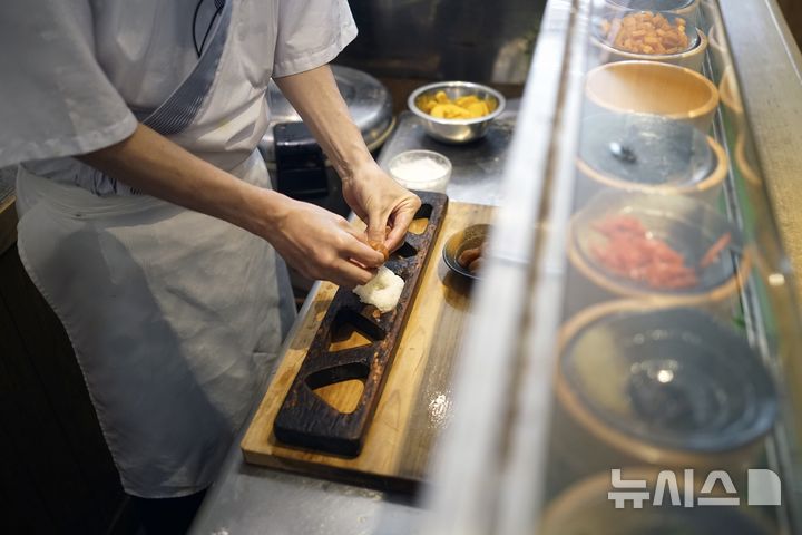 [도쿄=AP/뉴시스] 지난 2024년 6월 3일 일본 도쿄의 가장 오래된 주먹밥 전문점 '오니기리 아사쿠사 야도요쿠'에서 미우라 요스케가 구운 연어를 넣은 주먹밥을 만들고 있다. 한편, 일본에서는 올해 1~8월 창업 100년 이상 노포기업 112곳이 도산한 것으로 집계됐다. 2024.06.03.