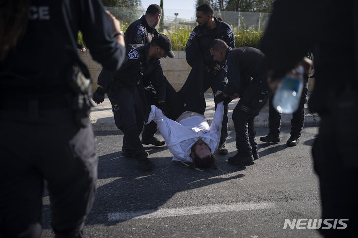 [AP/뉴시스] 이스라엘 대법원은 25일 그동안 징집 및 복무 의무에서 면제 혜택을 받았던 초정통 유대교 신자들에 대한 의무징집 개시를 명령하는 판결을 내렸다. 사진은 지난 2일 예루살렘에서 경찰이 시위에 나선 초정통 유대교 남성 신자를 강제로 거리에서 밀어내고 있는 모습.