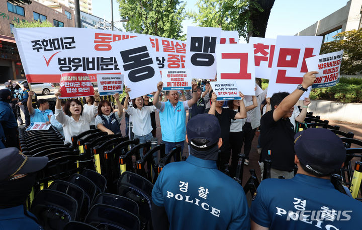 [서울=뉴시스] 김근수 기자 = 겨레하나와 서울자주통일평화연대 회원들이 25일 오전 서울 동대문구 한국국방연구원에서 열린 제12차 한·미 방위비분담특별협정(SMA) 4차 회의를 반대하는 손 피켓을 들고 미국측 대표단이 탄 버스를 향해 구호를 외치고 있다. 2024.06.25. ks@newsis.com