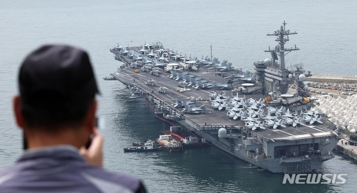 [부산=뉴시스] 하경민 기자 = 한국·미국·일본이 처음 실시하는 해상·수중·공중·사이버 등 다영역 군사훈련 '프리덤 에지'(Freedom Edge)에 참가하기 위해 미국 해군의 핵추진 항공모함 '시어도어 루스벨트'(CVN-71·10만t급)가 26일 부산 남구 해군작전사령부 부산작전기지에서 출항을 준비하는 모습을 한 시민이 지켜보고 있다. 2024.06.26. yulnetphoto@newsis.com