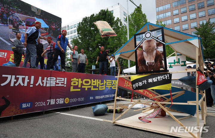 [서울=뉴시스] 김명년 기자 = 3일 오후 서울 영등포구 국회 앞에서 열린 '한우산업 안정화 촉구 한우 반납 투쟁' 집회에서 전국한우협회 회원들이 비료포대를 던져 소 축사를 부수는 퍼포먼스를 하고 있다. 2024.07.03. kmn@newsis.com