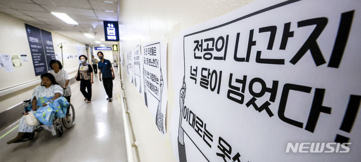 [서울=뉴시스] 정병혁 기자 = 정부가 이르면 이번 주 미복귀 전공의 관련 대책을 발표할 것으로 알려진 가운데 7일 서울시내 대학병원에 붙은 전공의 집단행동 중단을 촉구하는 인쇄물 옆으로 환자와 보호자들이 이동하고 있다. 2024.07.07. jhope@newsis.com