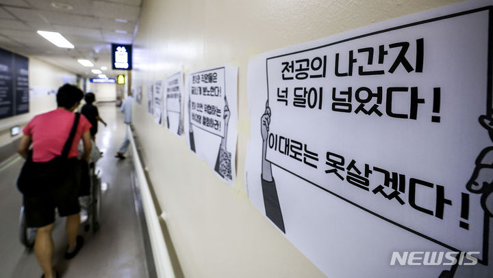 [서울=뉴시스] 정병혁 기자 = 정부가 이르면 이번 주 미복귀 전공의 관련 대책을 발표할 것으로 알려진 가운데 7일 서울시내 대학병원에 붙은 전공의 집단행동 중단을 촉구하는 인쇄물 옆으로 환자와 보호자들이 이동하고 있다. 2024.07.07. jhope@newsis.com