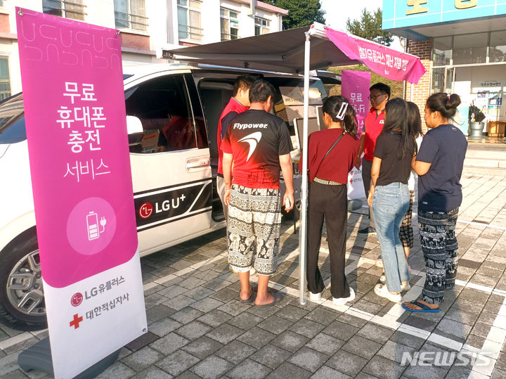 [서울=뉴시스]LG유플러스는 집중호우로 수해를 입은 전북 익산시에 마련된 재난 대피 구호소에 '휴대폰 배터리 충전 차량'을 보냈다고 11일 밝혔다. 사진은 LG유플러스 직원들이 수재민들에게 휴대폰 보조배터리를 나눠주고 있는 모습. (사진=LG유플러스 제공)