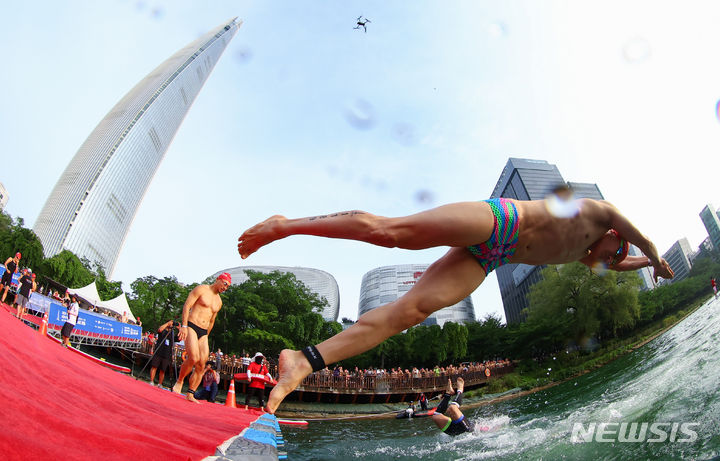 [서울=뉴시스] 황준선 기자 = 14일 오전 서울 송파구 롯데월드타워 일대에서 열린 '2024 롯데 아쿠아슬론 대회'에 출전한 참가자들이 석촌호수에서 출발하고 있다. 2024.07.14. hwang@newsis.com