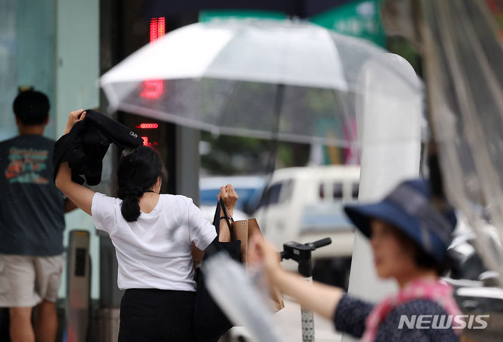 [서울=뉴시스] 김명년 기자 = 비가 내린 16일 오후 서울 중구 회현사거리에서 한 시민이 겉옷으로 비를 피하며 발걸음을 재촉하고 있다. 2024.07.16. kmn@newsis.com