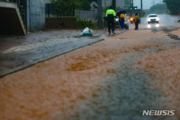 [서울=뉴시스] 김명년 기자 = 파주시와 연천군 등 경기북부 8개 시·군에 호우특보가 발효된 17일 오전 경기 파주시 광탄면의 한 도로가 침수돼 면사무소 관계자들이 배수 작업을 하고 있다. 2024.07.17. kmn@newsis.com
