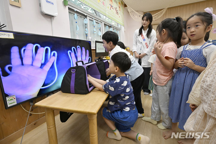 [광주=뉴시스] 박기웅 기자 = 광주 북구보건소 주최로 18일 북구청어린이집에서 열린 여름철 식중독 예방을 위한 '올바른 손씻기 교실에서 감염병관리팀 직원들이 아이들에게 뷰박스를 이용해 손을 씻기 전과 후 청결상태를 보여주고 있다. 2024.07.18. pboxer@newsis.com