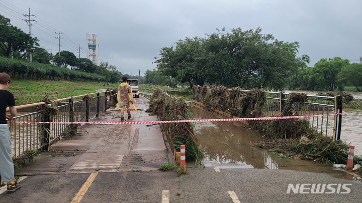 [오산=뉴시스] 집중호우로 부유물이 걸린 오산천변 청소