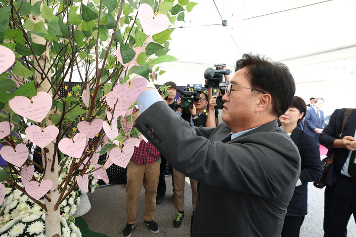 [서울=뉴시스] 우원식 국회의장이 19일 오후 종로구 서울시교육청에 마련된 서이초 순직 교사 1주기 추모 공간에 자신이 작성한 추모 메시지를 걸고 있다. 우 의장은 '선생님을 잊지 않겠습니다!'라고 적었다. (사진=서울시교육청 제공). 2024.07.19. photo@newsis.com *재판매 및 DB 금지