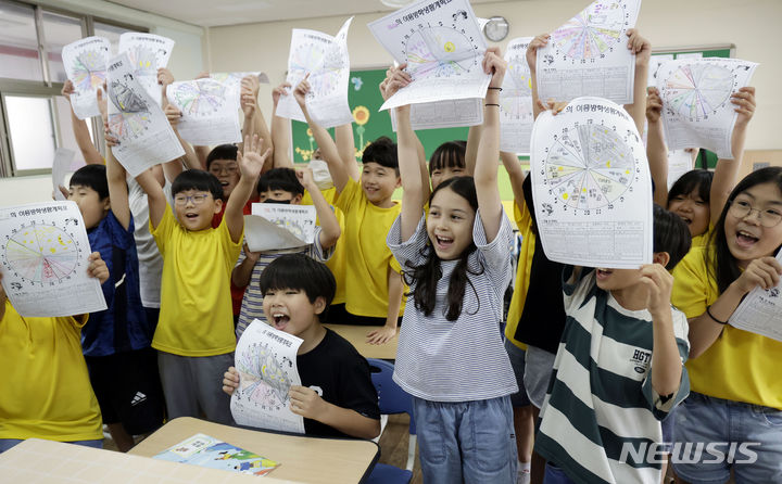 [서울=뉴시스] 최동준 기자 = 19일 서울 동작구 대림초등학교에서 4학년 5반 학생들이 여름방학식에서 방학생활계획표를 들어보이며 즐거워하고 있다. 2024.07.19. photocdj@newsis.com