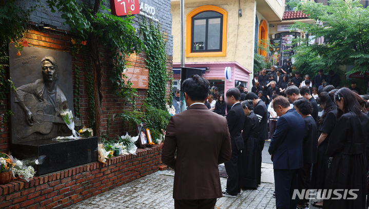 [서울=뉴시스] 전신 기자 = 30여년간 대학로 소극장 '학전'을 운영하며 후배 예술인 배출에 힘썼던 가수 고(故) 김민기의 발인식이 엄수된 24일 서울 종로구 '학전'이 폐관된 후 새롭게 연 극장인 아르코꿈밭극장에서 유가족들이 추모 묵념을 하고 있다. 2024.07.24. photo1006@newsis.com