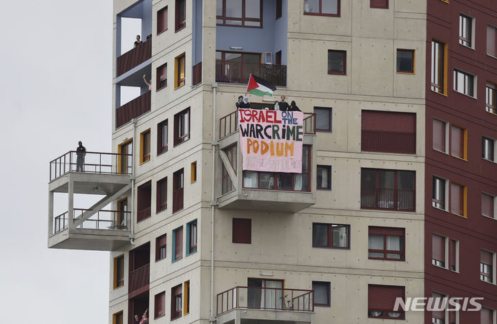 [파리=AP/뉴시스] 가자지구 전쟁과 중동 지역 갈등으로 이스라엘의 전운이 확대되는 가운데, 2024 파리올림픽에 참가한 이스라엘 선수들이 각종 증오 범죄에 노출되고 있다. 사진은 지난달 26일 열린 올림픽 개회식 당시 파리의 한 건물 발코니에서 일부 관중이 '이스라엘은 전쟁 범죄 포디움에 섰다'고 적힌 플래카드를 들고 있는 모습. 2024.08.07.