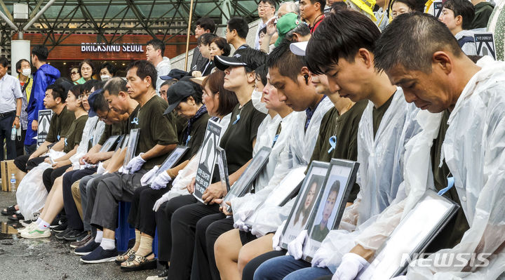 [서울=뉴시스] 정병혁 기자 = 27일 서울 중구 서울역 광장에서 열린 아리셀 중대재해 참사 희생자 시민추모제에서 유가족들이 희생자 영정을 든 채 고개를 숙이고 있다. 2024.07.27. jhope@newsis.com