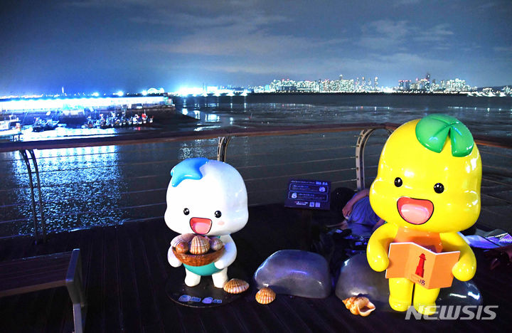 [시흥=뉴시스] 박석희기자=빨간 등대 앞에 자리한 해로·토로 캐릭터 조형물이 조명등이 화려한 오이도 밤의 운치를 더하고 있다. 2024.7.30. photo@newsis.com *재판매 및 DB 금지