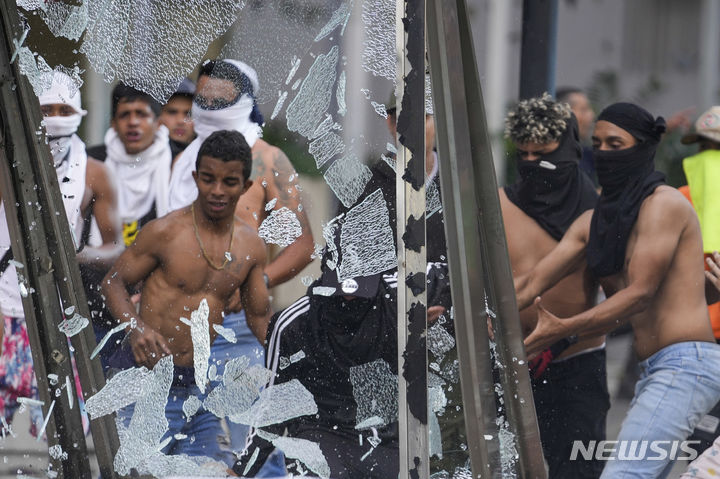 [카라카스=AP/뉴시스] 29일(현지시각) 베네수엘라 카라카스에서 니콜라스 마두로 대통령의 3선 선거 결과에 반대하는 시위대가 거리의 광고판을 부수고 있다. 베네수엘라 대선을 둘러싼 부정·불공정 정황이 쏟아지면서 이에 항의하는 유권자들의 시위가 거세지고 있다. 2024.07.30.