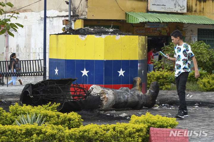 [발렌시아=AP/뉴시스] 30일(현지시각) 베네수엘라 발렌시아에서 한 시민이 대선 불복 시위대에 의해 파괴된 고(故) 우고 차베스 전 대통령 동상을 바라 보고 있다. 시위대와 경찰의 충돌로 700명이 구금되고 사상자도 속출하고 있다.