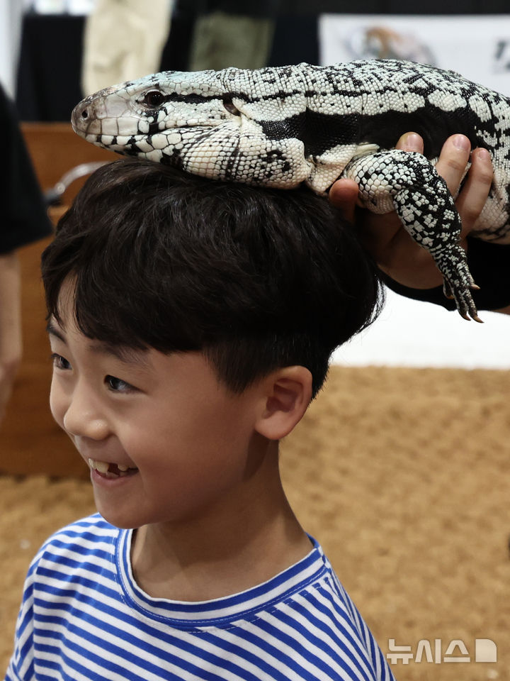 [서울=뉴시스] 김금보 기자 = 4일 서울 강남구 SETEC에서 열린 한국 파충류쇼를 찾은 어린이가 도마뱀과 촬영을 하고 있다. 2024.08.04. kgb@newsis.com