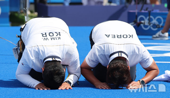 [파리=뉴시스] 김진아 기자 = 김우진이 4일(현지시각) 프랑스 파리 레쟁발리드에서 열린 2024 파리 올림픽 양궁 남자 개인전 결승 미국 브레이디 엘리슨과의 경기에서 슛오프 접전 끝에 승리하며 금메달을 확정한 뒤 박성수 감독과 함께 큰절을 하고 있다. 2024.08.04. bluesoda@newsis.com