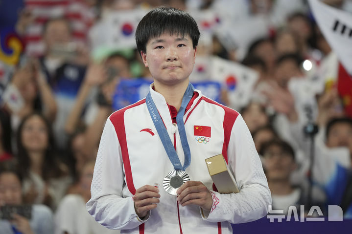 [파리=AP/뉴시스]허빙자오(중국)가 5일(한국시각) 프랑스 파리 포르트드라샤펠 경기장에서 열린 2024 파리 올림픽 배드민턴 여자 단식 결승전 시상식에서 은메달과 함께 스페인 팀 배지를 들어 보이고 있다. 2024.08.06.