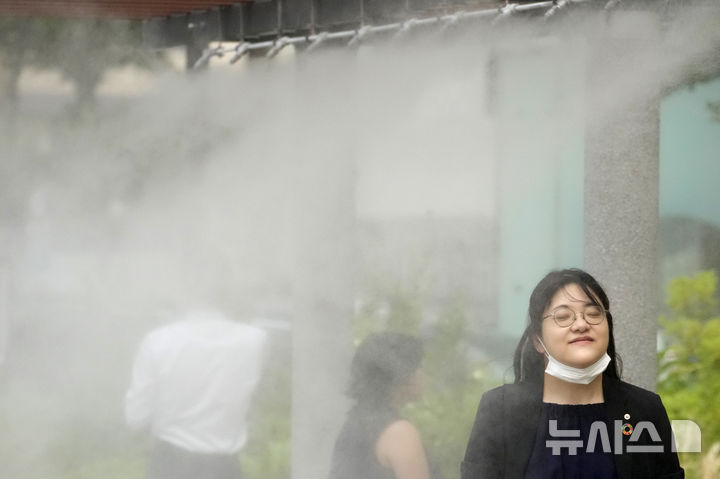 [도쿄=AP/뉴시스]일본 수도 도쿄(東京)도가 올해 여름 수개월 간 더위 대책으로서 일반 가정에 대한 수도 기본요금을 감면하는 방침을 굳혔다고 요미우리신문, 마이니치신문 등이 20일 보도했다. 지난해 7월 4일 일본 도쿄에서 더위를 식히기 위해 마련된 '쿨링 미스트 스팟'을 시민들이 지나가고 있다. 2025.05.20.