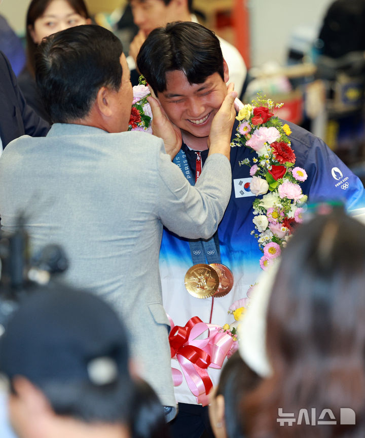 [인천공항=뉴시스] 고범준 기자 = 2024 파리 올림픽 양궁 전 종목에서 금메달을 획득한 대한민국 양궁 대표팀 이우석이 6일 오전 인천국제공항 제2여객터미널을 통해 귀국해 꽃목걸이를 걸고 활짝 웃고 있다. 2024.08.06. bjko@newsis.com